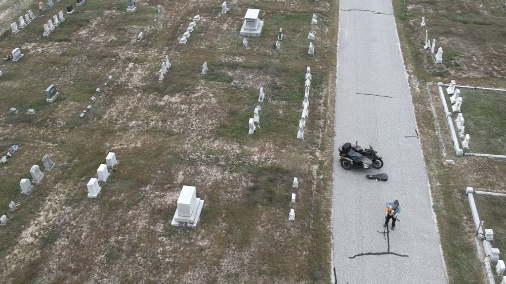 Musician in a cemetery with a motorcycle